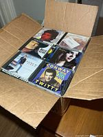 Open box showing top layer of various CDs including Willie Nelson and Conway Twitty