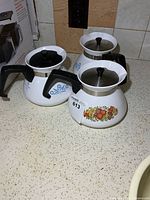 Three Corning Ware teapots showing patterns and lids
