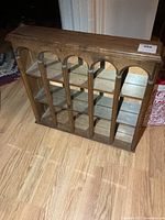 Front view of wooden display shelf showing arched trim, shelves and mirrored back