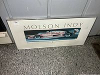 Full view of framed Molson Indy poster leaning against wall