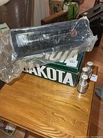 Plastic display stand in bag on top of green box with four miniature Stanley Cup trophies