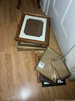 Stack of wood and metal picture frames on floor
