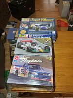Stack of three sealed racing model kit boxes on table
