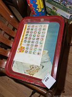 Red metal tray with commemorative sheet on top