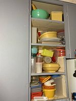 Full cupboard view showing stacked Tupperware bowls, containers, colander, lids