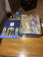 tin with lid showing assorted contents