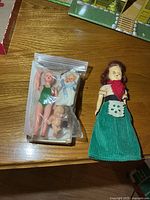 Bagged set of four miniature dolls beside larger doll