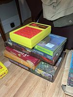 Stack of board games with Perfection unit on top, showing Scrabble and Fortress America boxes