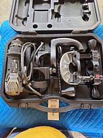 Open case showing rotary cutter, cord, attachments in molded slots