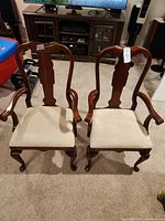Front view of two matching wood armchairs with upholstered seats