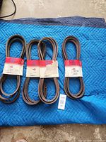 Four Rotary belts on blue blanket, shows quantity