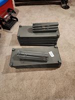 Two stacks of rectangular dark gray shelf plates with bundled support tubes on top