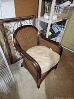 Front three-quarter view showing wicker weave, wooden trim, tan cushion