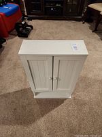 Front view closed, showing white two-door cabinet