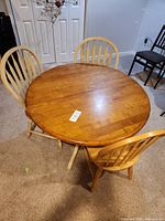 Round wood dining table with three wood spindle-back chairs