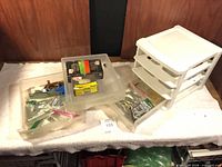 Overall view showing white 3-drawer plastic storage unit beside clear trays filled with hardware