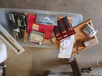 Top view of tote showing packed paint brushes, stationery, ink cartridge, cork board, push pins, compass