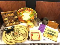 Full group shot showing all items including platter, shadowbox, metal pieces, baking dishes, placemats, silicone mold and trivet