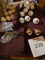 mixed knobs and hardware laid out including ceramic floral, wood, brass and screws