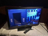 TV powered on displaying image, remote on stand