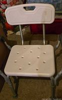 White plastic shower chair with aluminum legs and backrest