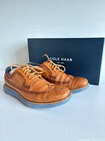 Pair of tan Cole Haan Lunargrand shoes with box frontal view