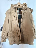 Full view of tan Eddie Bauer parka on hanger, front open showing lining