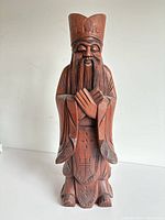 Front view of carved wood statue showing facial details, hands and robe
