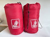 Two red Hillary sleeping bags in stuff sacks