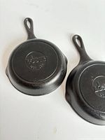 Two Lodge cast iron skillets upside down showing embossed bases