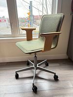 Side view showing green upholstery, bentwood arms, aluminum base on casters