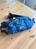 Front view of blue MEC fanny pack showing brand logo and zip pocket