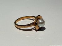 Side view of yellow gold ring showing pearl set on circular bezel