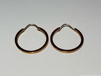 Pair of gold hoop earrings laid flat, showing square-edge design