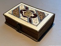 Closed book showing ornate top cover with metal frame and clasp