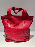 Front view of red leather tote displaying woven panels