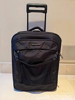 Front view of black Briggs & Riley rolling carry-on showing front pockets and overall condition