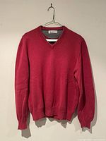 Full front view of raspberry red V-neck sweater on hanger