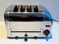 Front view of chrome Dualit 4-slice toaster showing four slots, control knob, and red switch