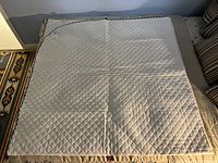 Full view of white quilted coverlet laid flat