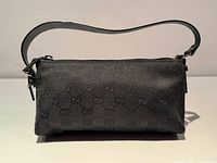 Front view of Gucci black GG canvas baguette bag