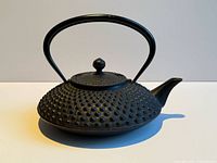 Side view of black cast iron hobnail teapot