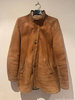 Front view of tan shearling coat on hanger