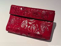 Front view of red crocodile leather clutch showing flap and scale pattern