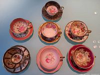 Seven floral teacup and saucer sets displayed on table