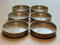 Six coasters arranged flat showing sterling rims and crystal starburst bases
