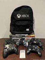 Overall lot showing backpack, game stack and five controllers