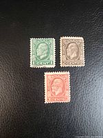 Three Canadian King George V Medallion stamps denominations 1c green, 2c brown, 3c red on black background