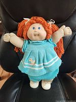 Front view of doll seated on chair
