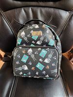 Front view of black Naruto mini backpack showing character print and metal emblem